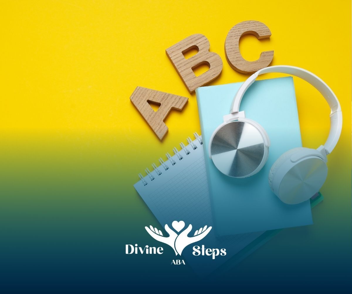 A pair of headphones sitting on top of a notebook next to the letters abc