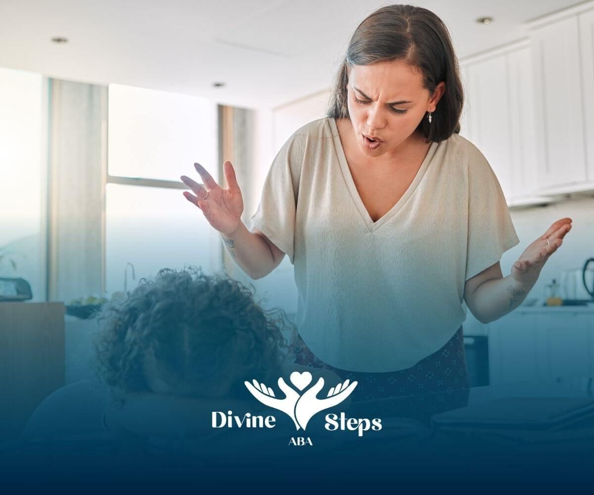 A therapist raising hands while speaking to upset autistic girl resting head on book at the table.