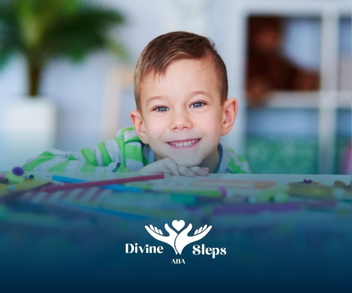 A young boy with autism is sitting at a table with a pile of colored pencils in ABA therapy.