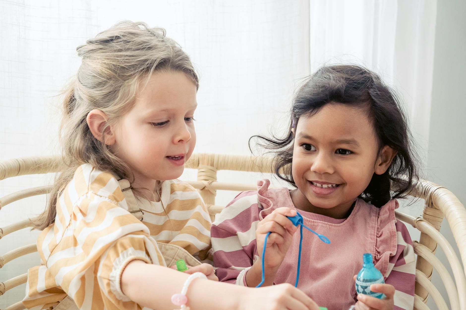 Two young autistic girls smiling and playing with small craft bottles and strings in Maryland.