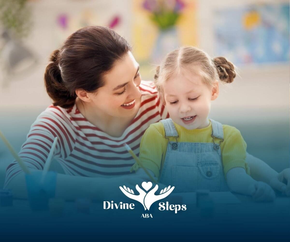 A BCBA and a little girl are sitting at a table painting in ABA therapy.