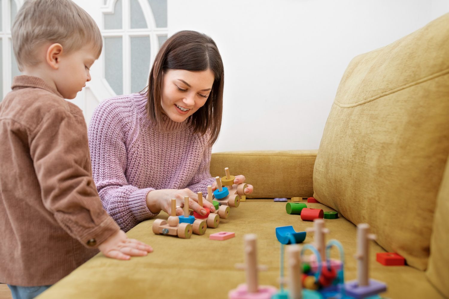 A and a child are playing with wooden toys on a couch.