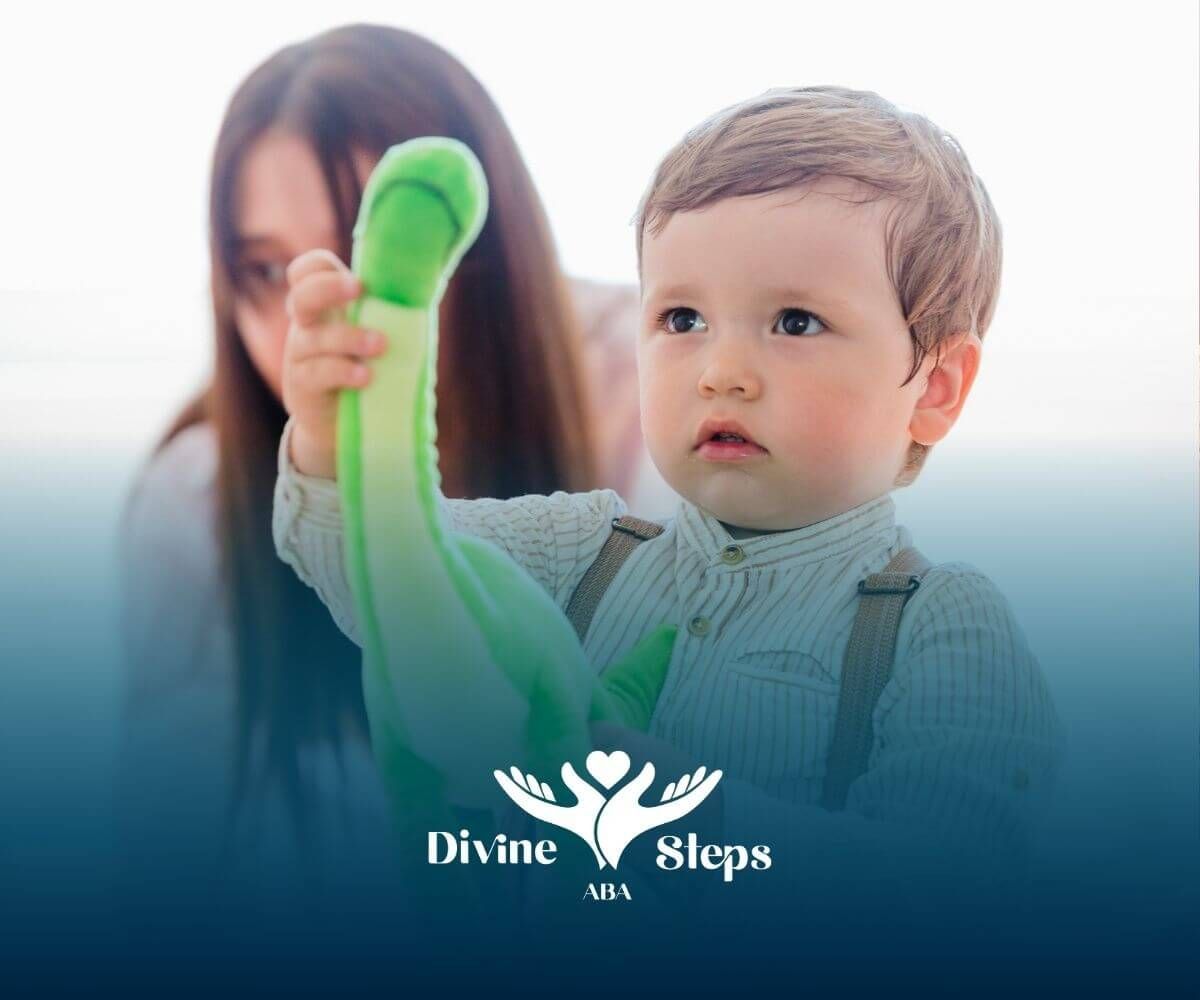An autistic baby is holding a stuffed dinosaur while in ABA therapy.