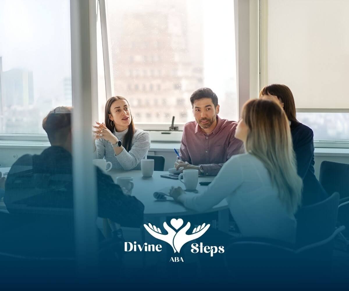 Diverse ABA therapists meeting around a table in a bright office, discussing plans and collaboration