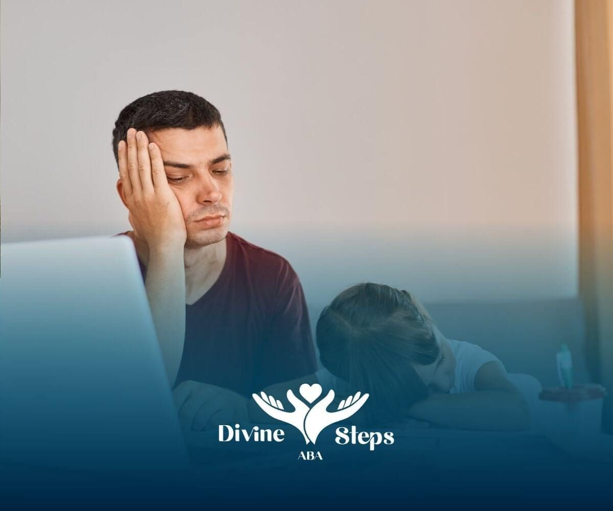 Tired BCBA and autistic child sitting at a desk with laptop and books in ABA therapy.