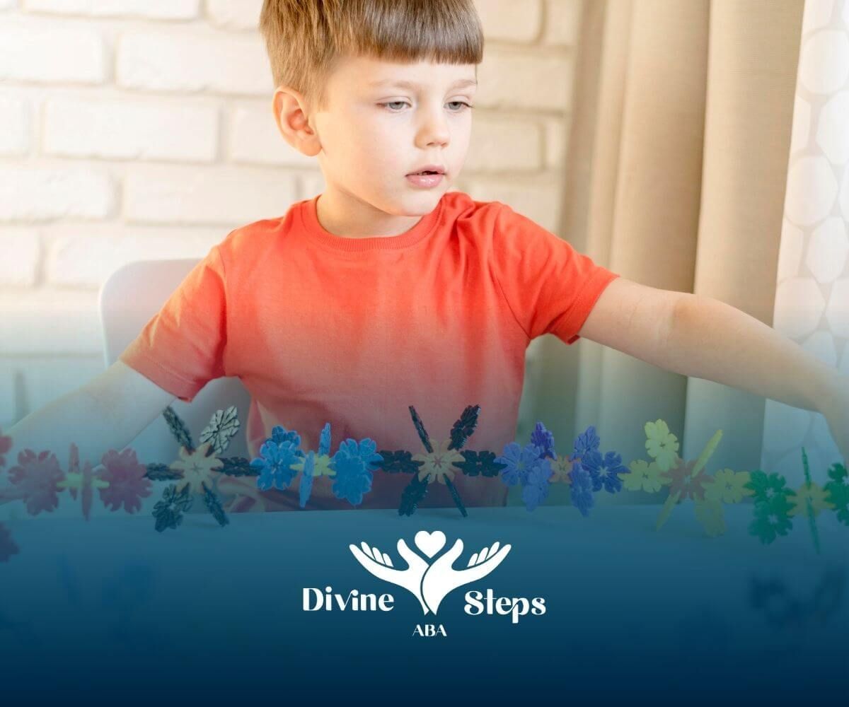 Autistic boy in orange shirt building a long chain of colorful plastic construction toys at table.
