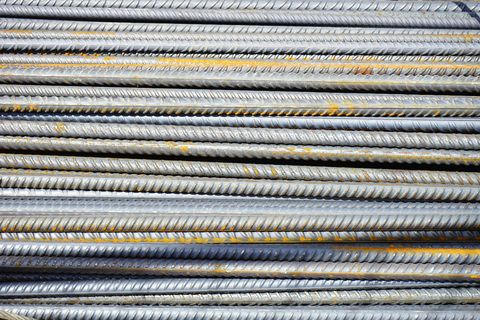 Pile of steel rebar, the ridged rods stacked horizontally, showing some rust.