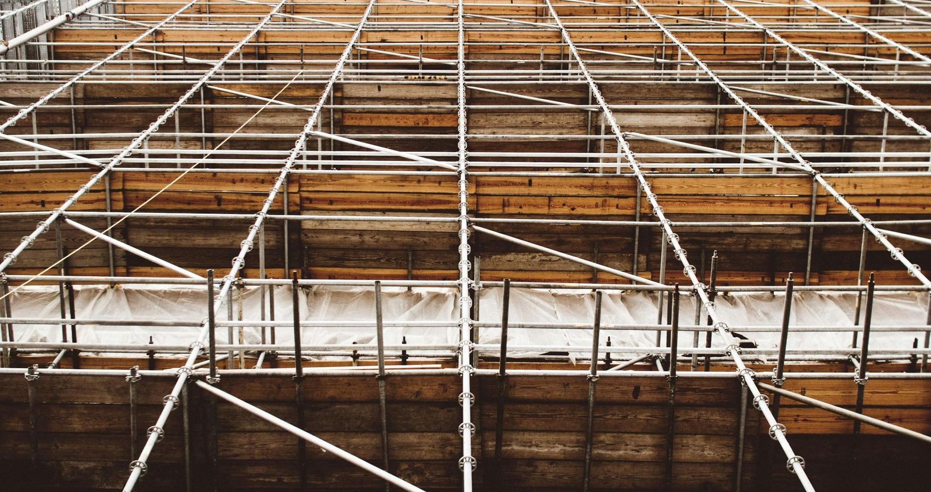 Close-up view of scaffolding on a building with horizontal and diagonal metal and wood beams.