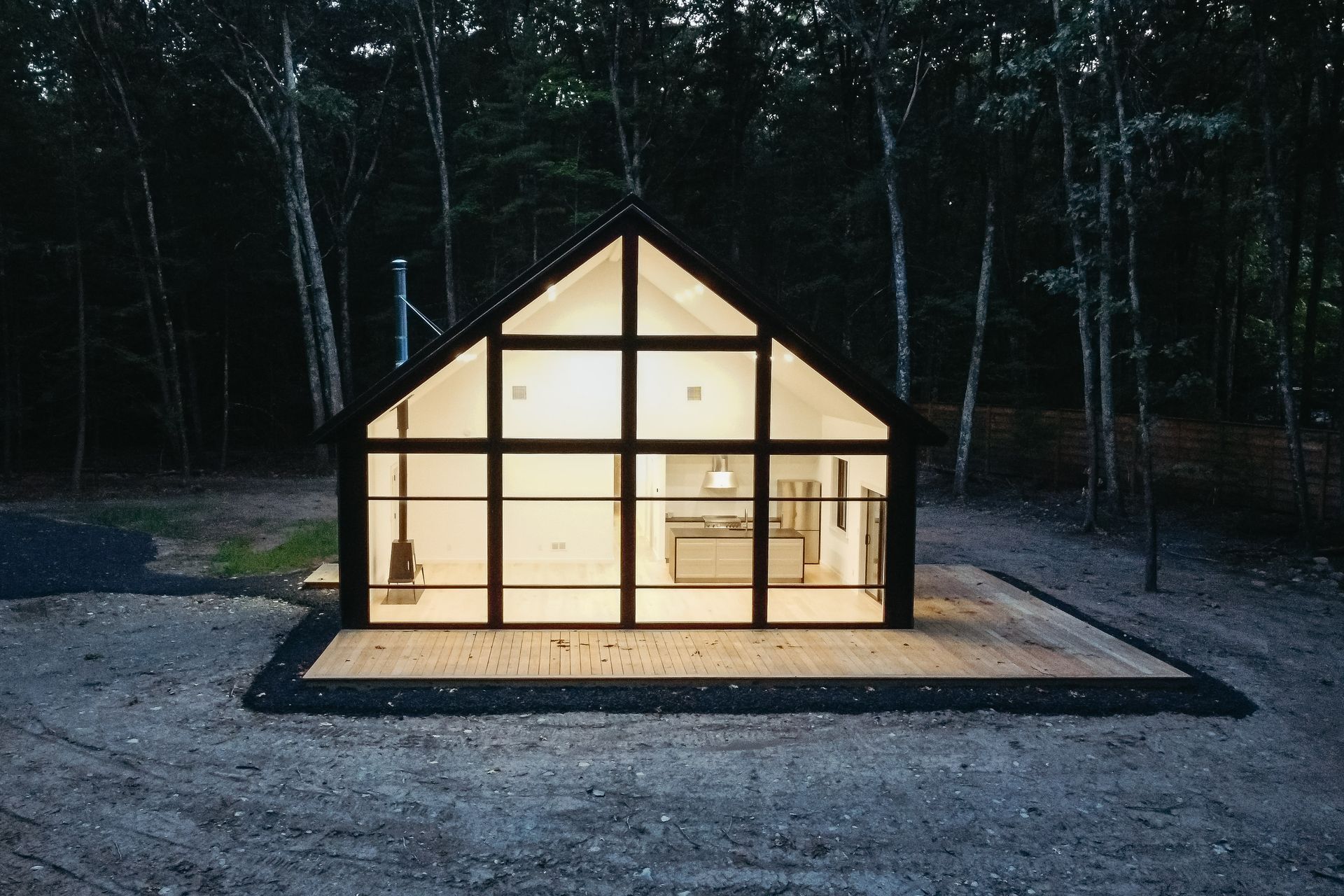 A small house with a lot of windows is lit up at night.