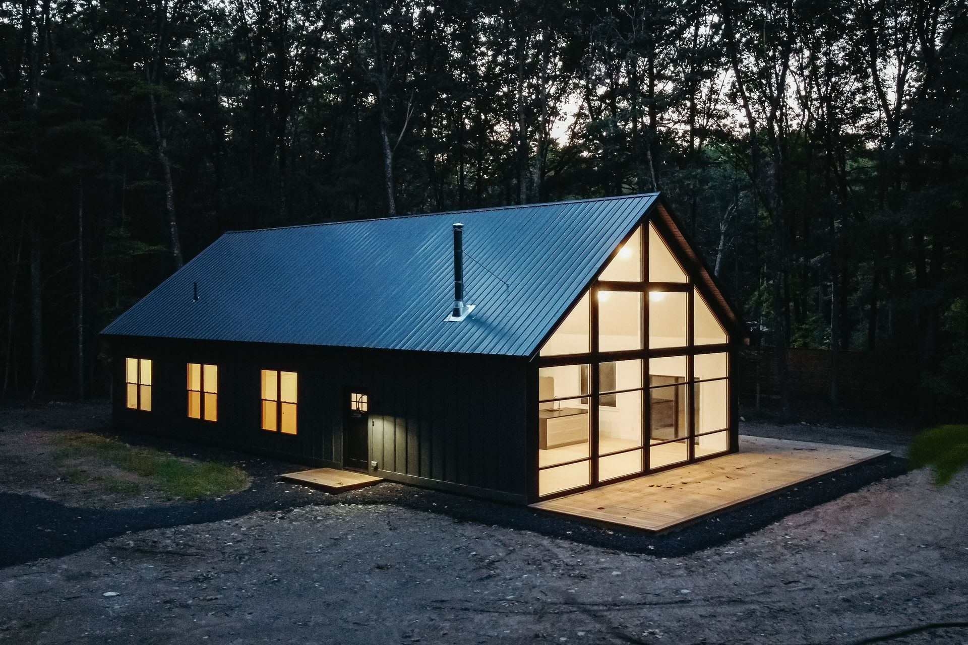 A black house with a lot of windows is lit up at night