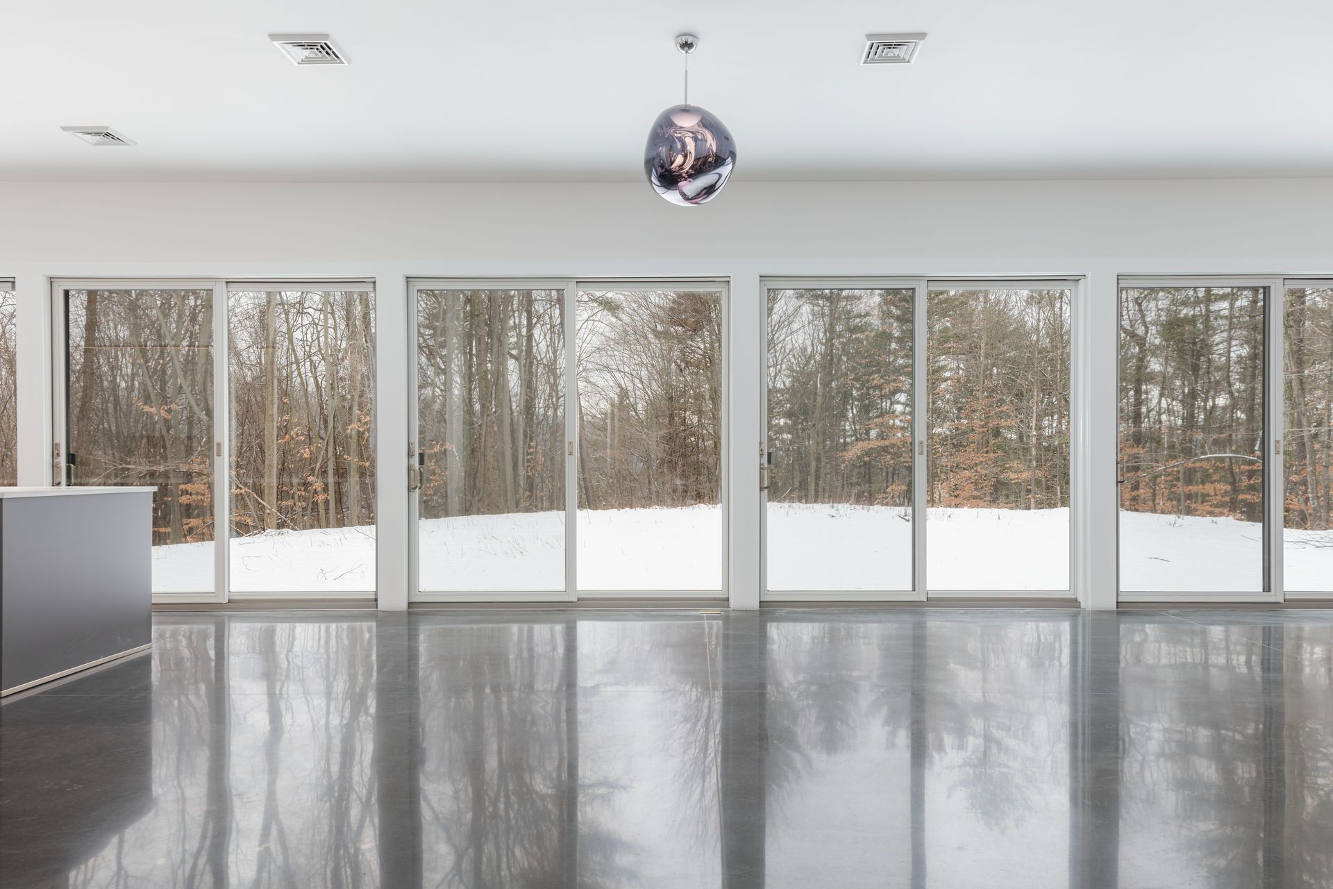 A large empty room with a lot of windows and trees in the background.
