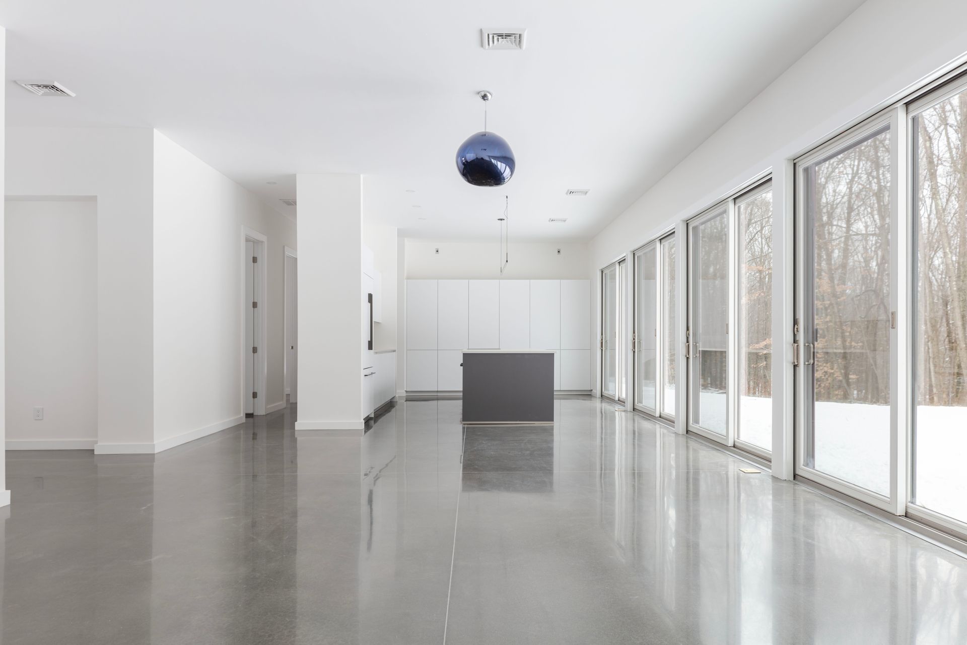 A large empty room with a lot of windows and a kitchen.