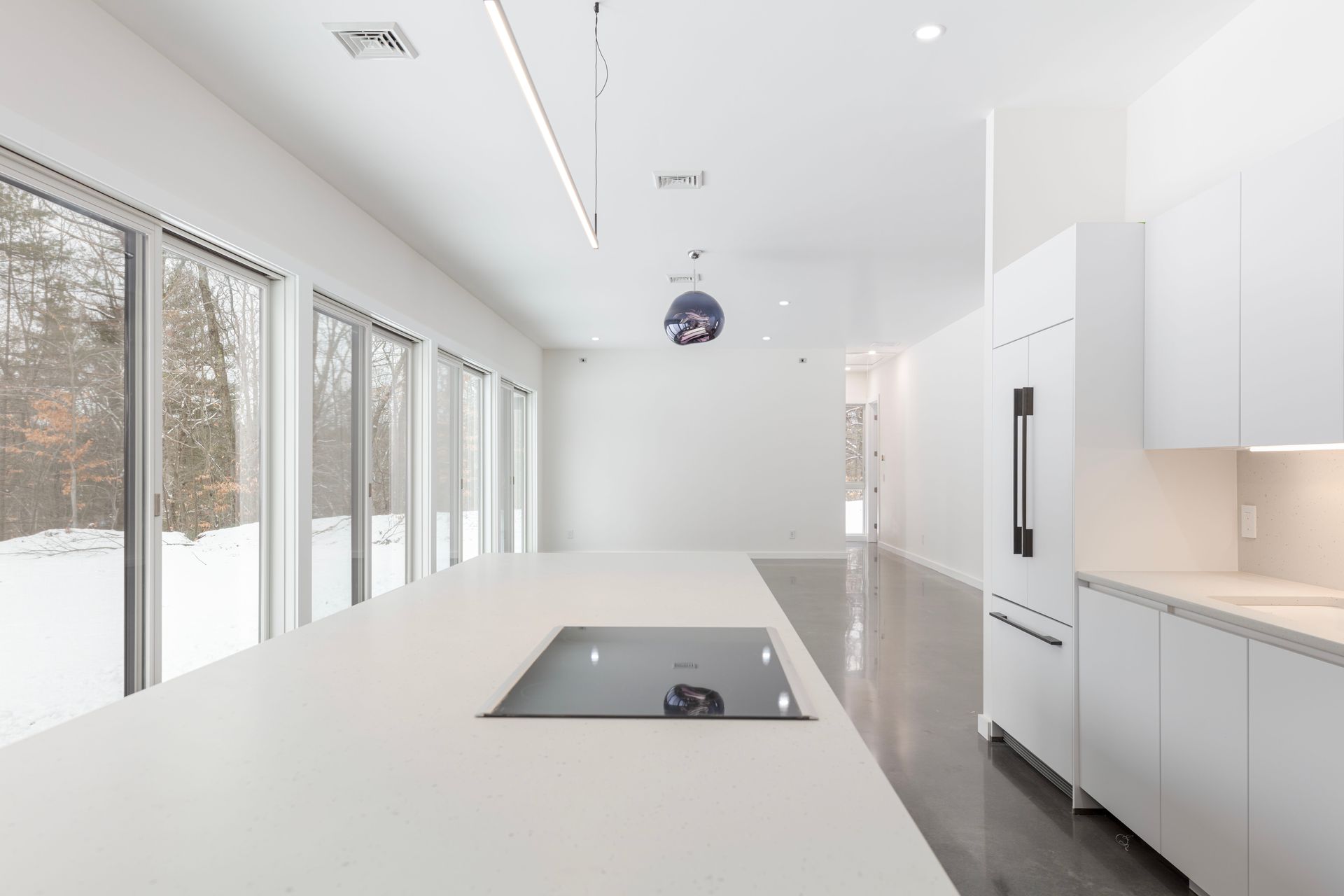 An empty kitchen with white cabinets and a stove top oven.