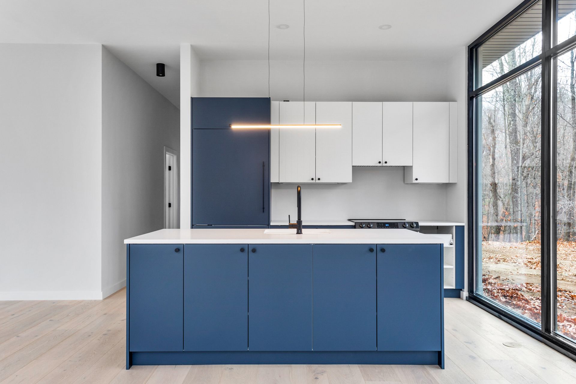 A kitchen with blue cabinets and white counter tops and a large island.