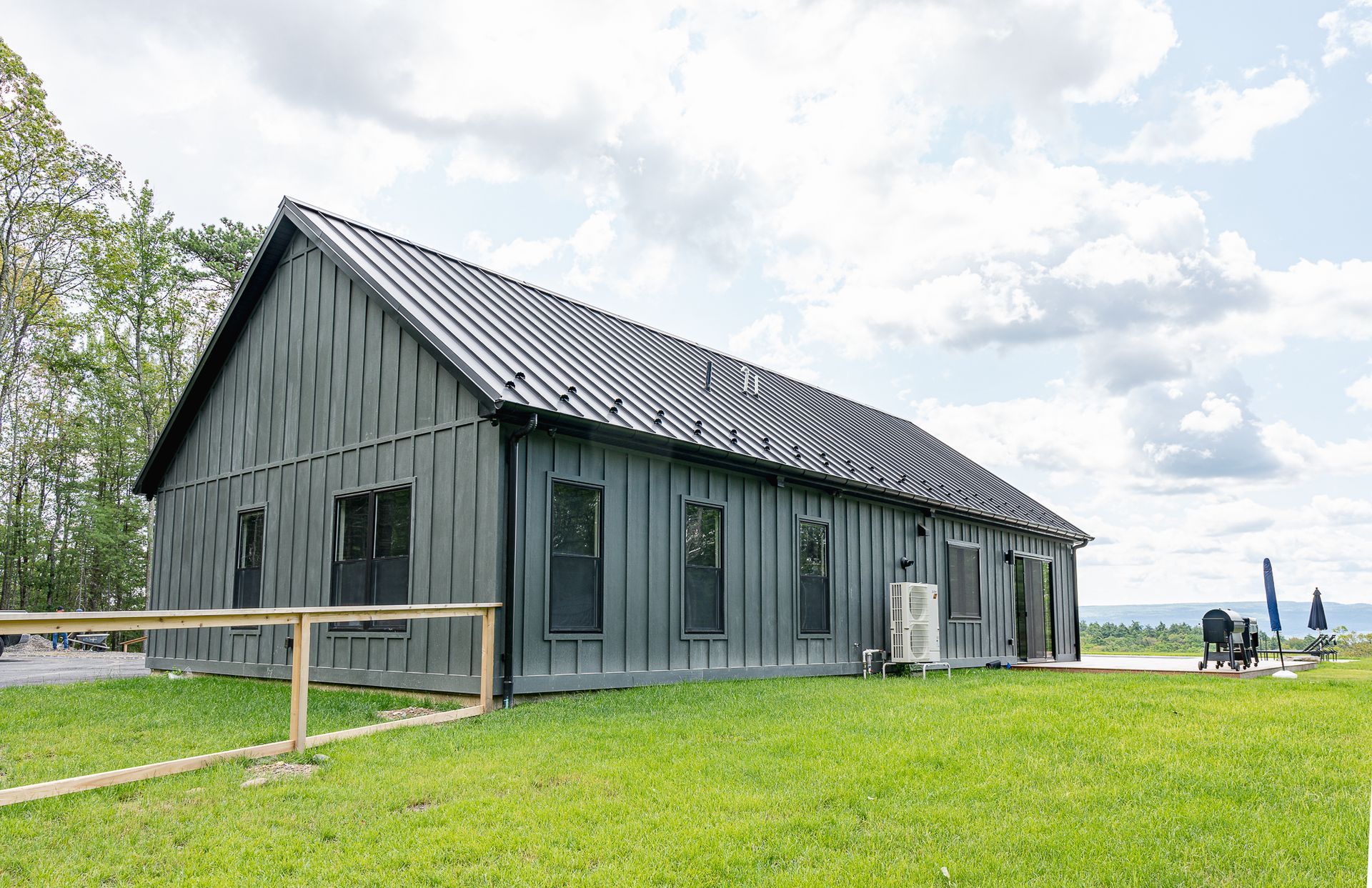 A large black barn is sitting on top of a lush green field.