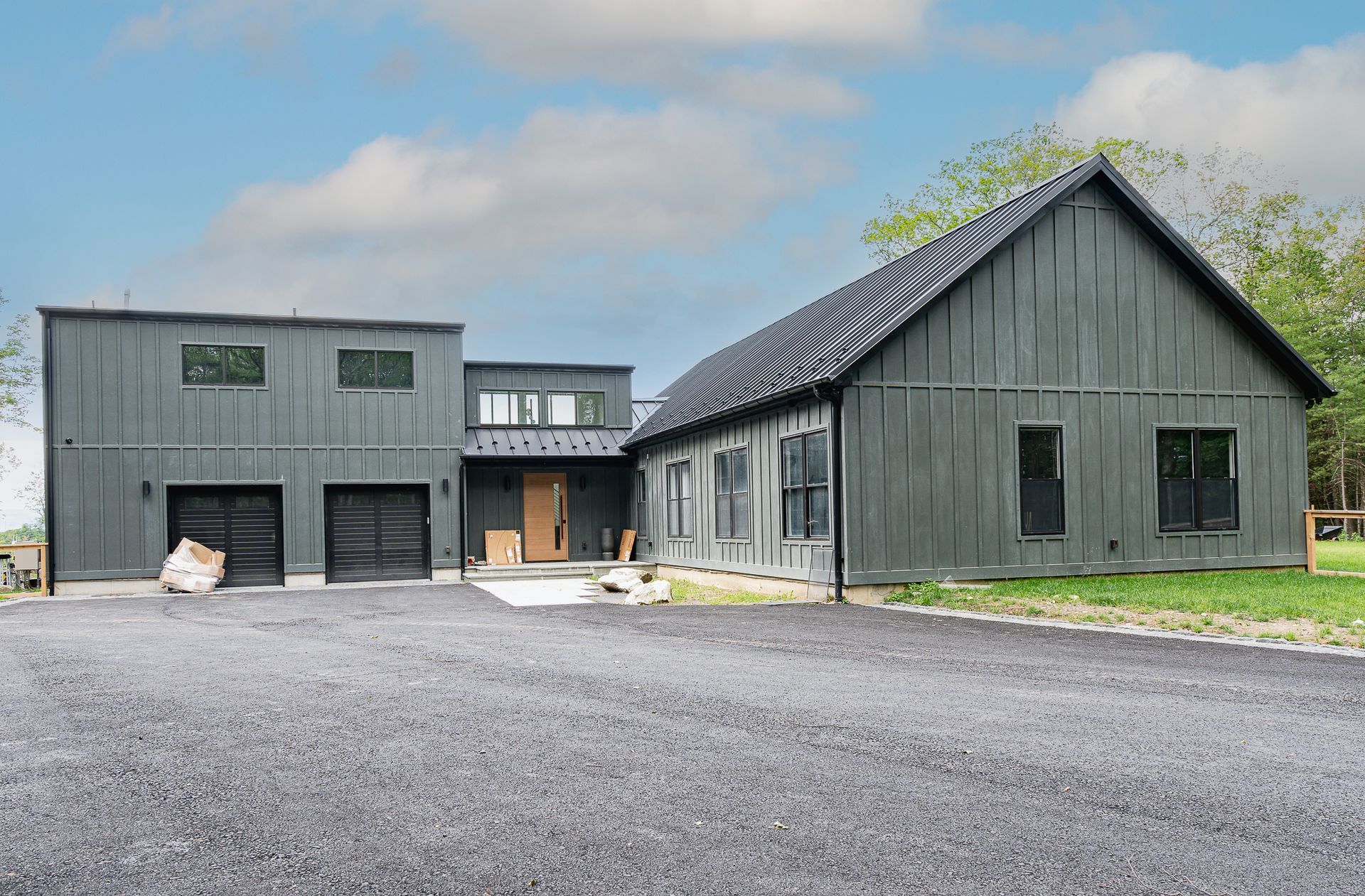 A large black house with a garage and a driveway in front of it.