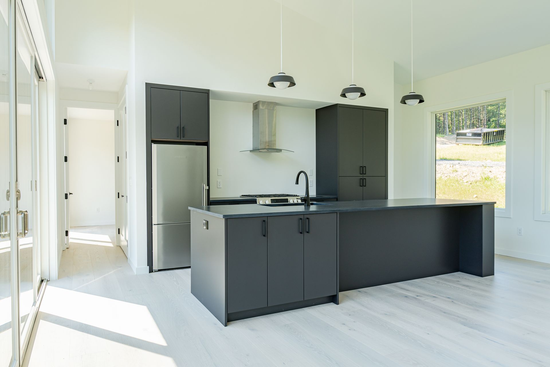 A kitchen with black cabinets and stainless steel appliances in a house.