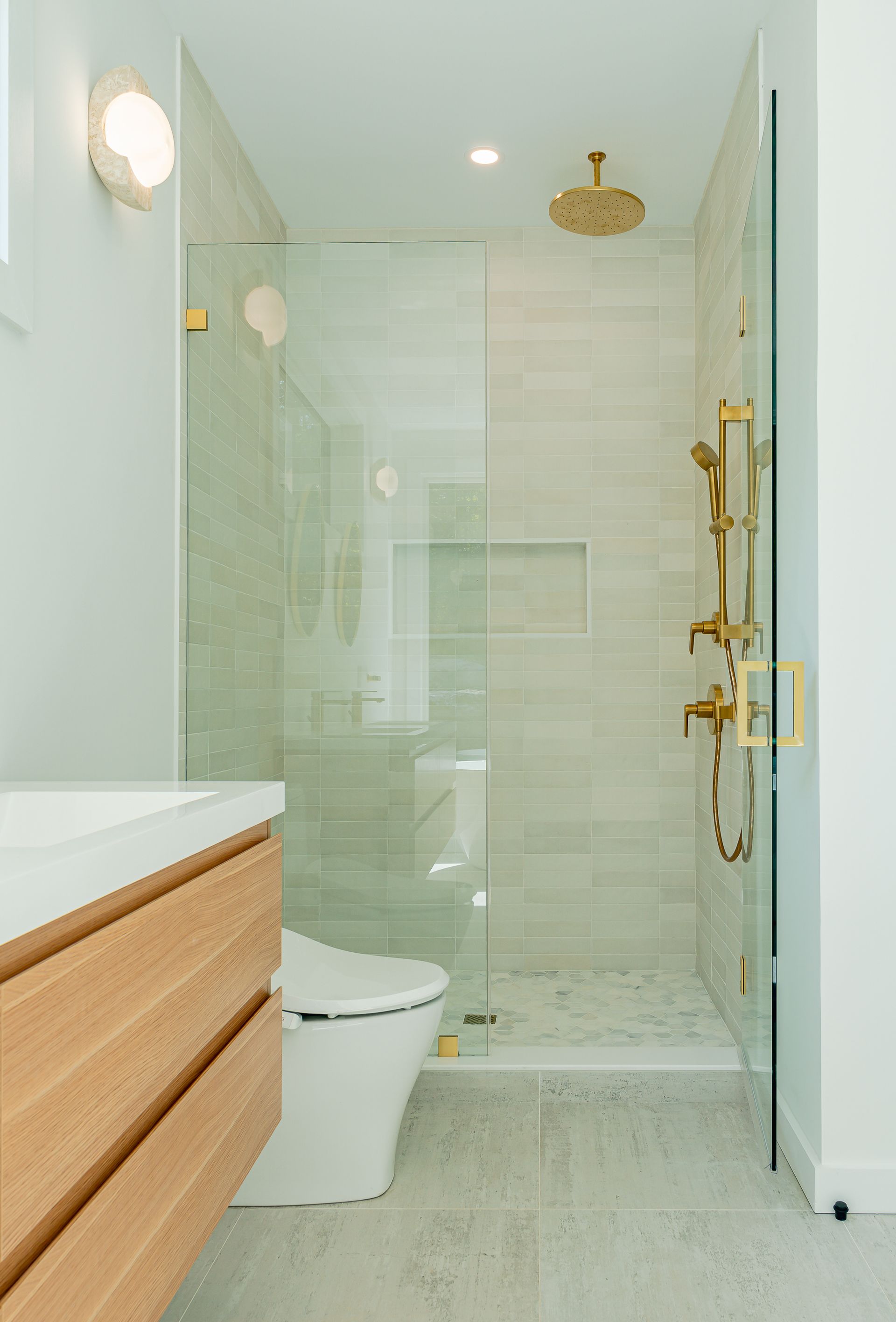 A bathroom with a toilet , sink and walk in shower.