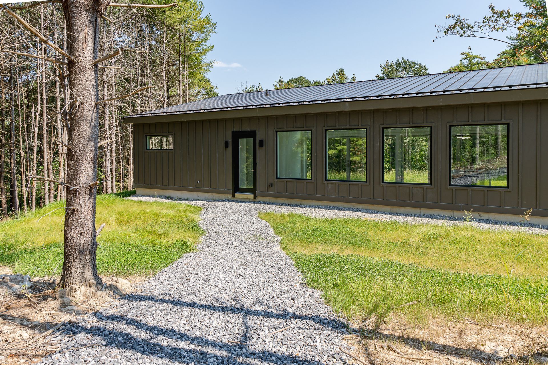 A house with a lot of windows and a gravel path leading to it.