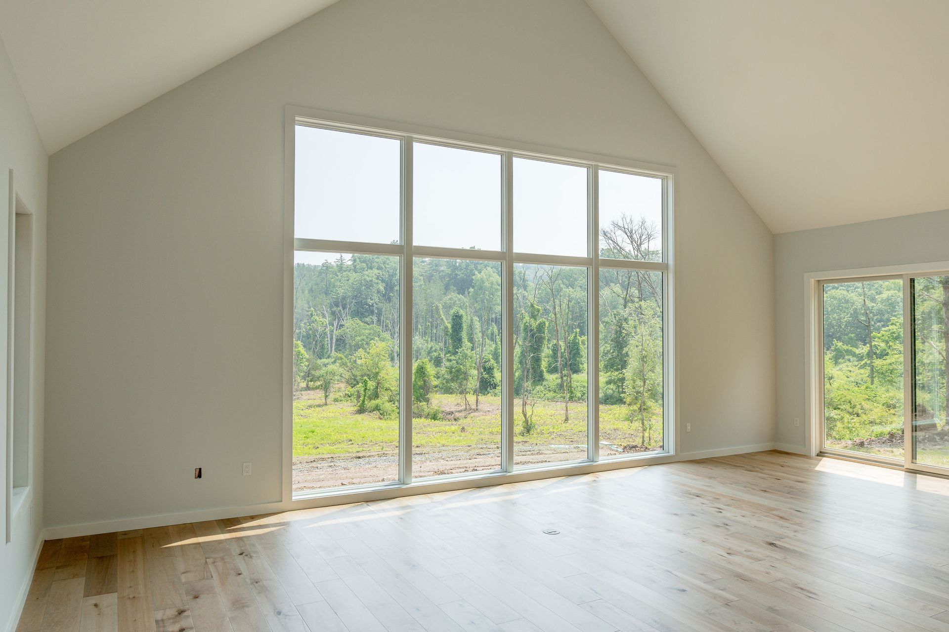 A large empty room with lots of windows and hardwood floors.