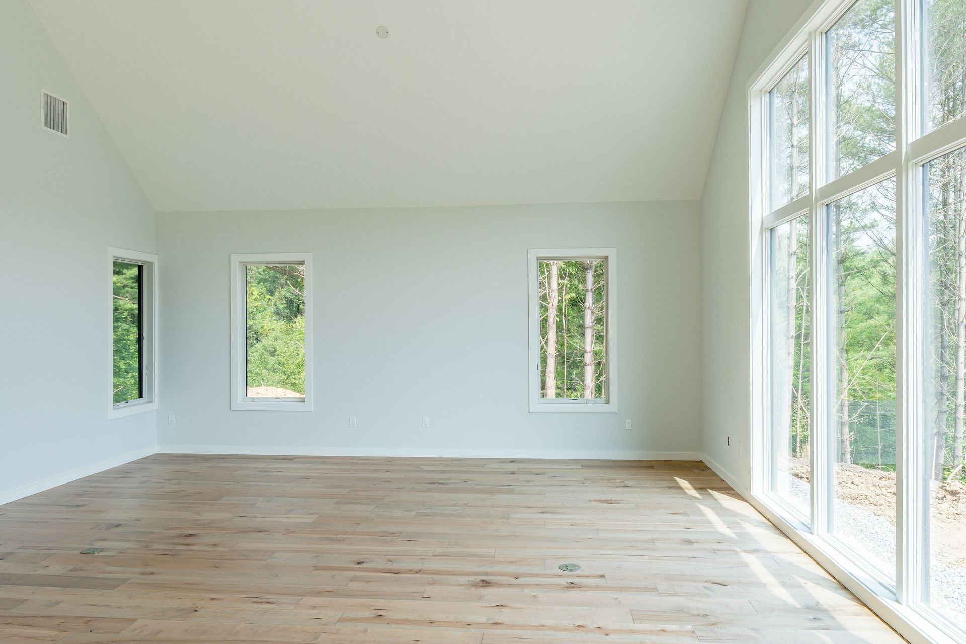 An empty room with hardwood floors and lots of windows.