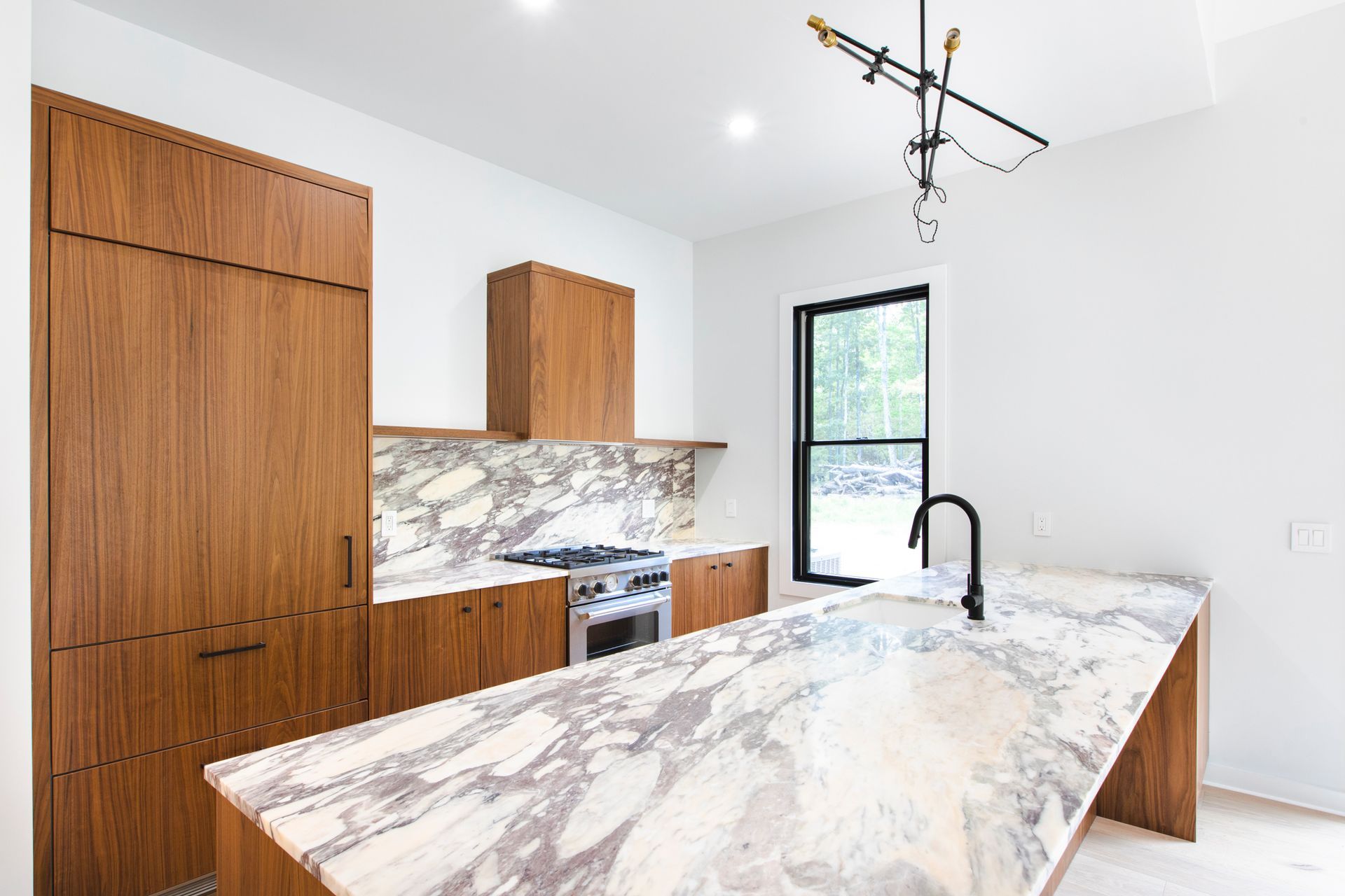 A kitchen with marble counter tops , wooden cabinets , stainless steel appliances and a large island.