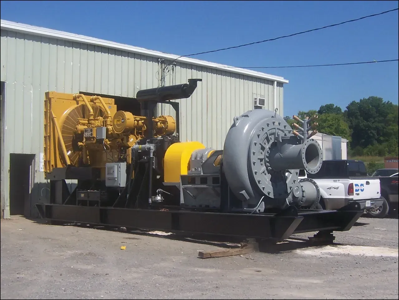 A large yellow and gray machine is parked in front of a building