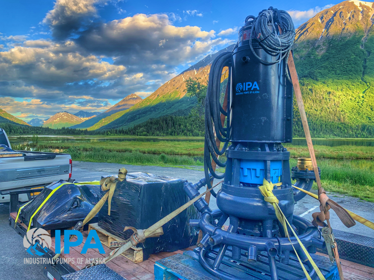 A large pump is sitting on top of a concrete block in front of a mountain.