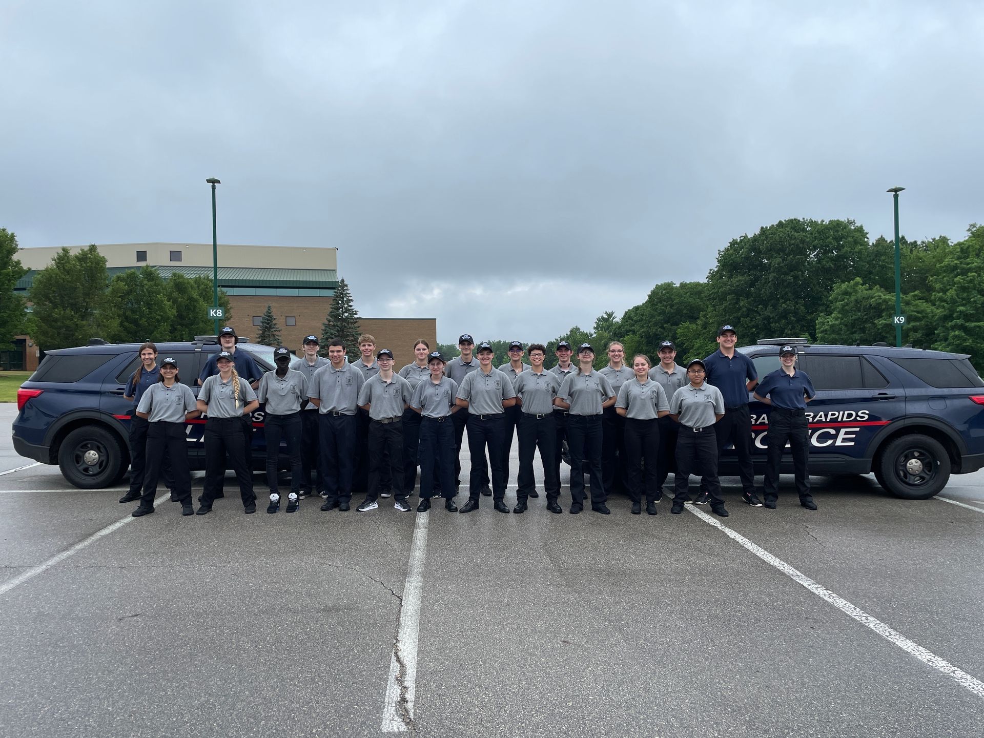 Group of people in matching hats and shirts, one wearing a vest, smiling outdoors.