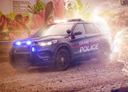 Police SUV from Grand Rapids, surrounded by electric-like energy, in front of graffiti.