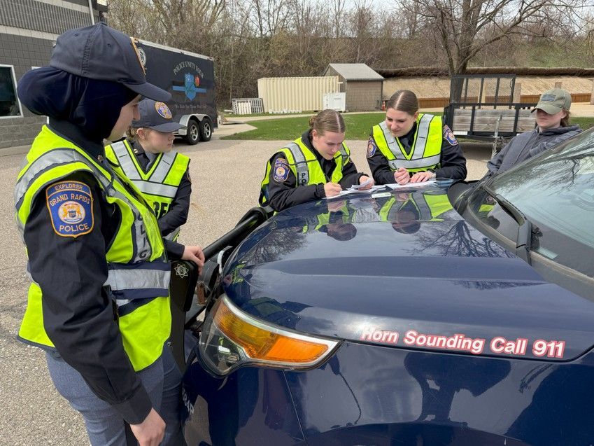 Four people in navy blue uniforms walk outside, smiling.