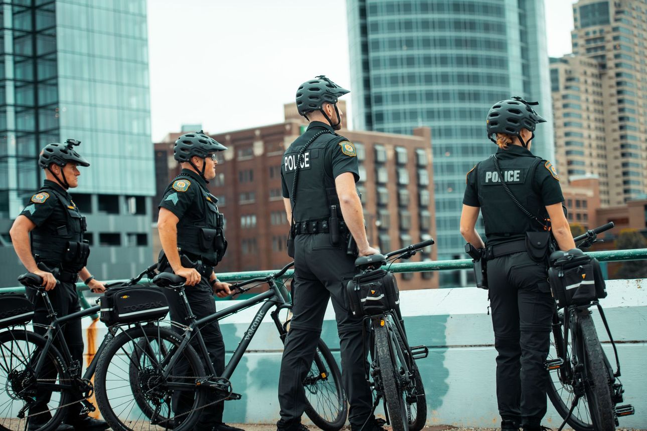 A police officer kneels, smiling, with a family in a cafe.