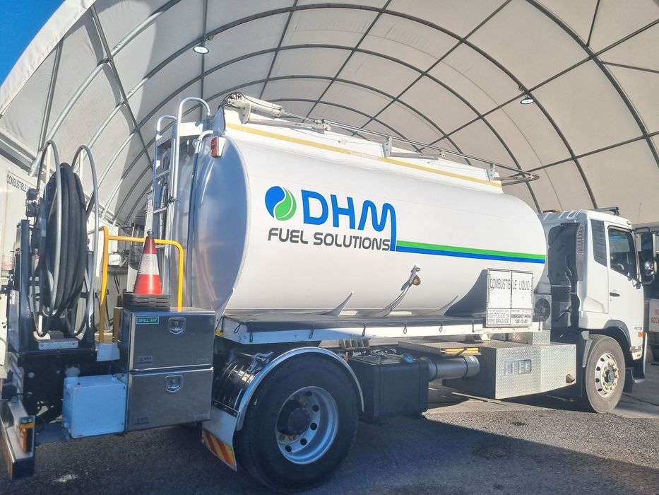 Fuel truck with DHM Fuel Solutions logo parked under a white canopy.