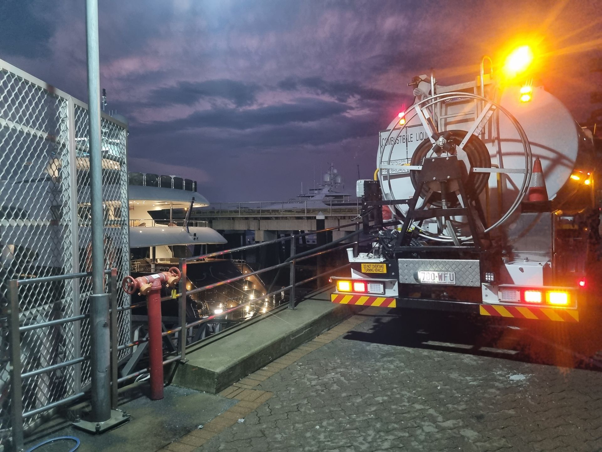 A utility truck with a large reel parked near a pier at dusk.