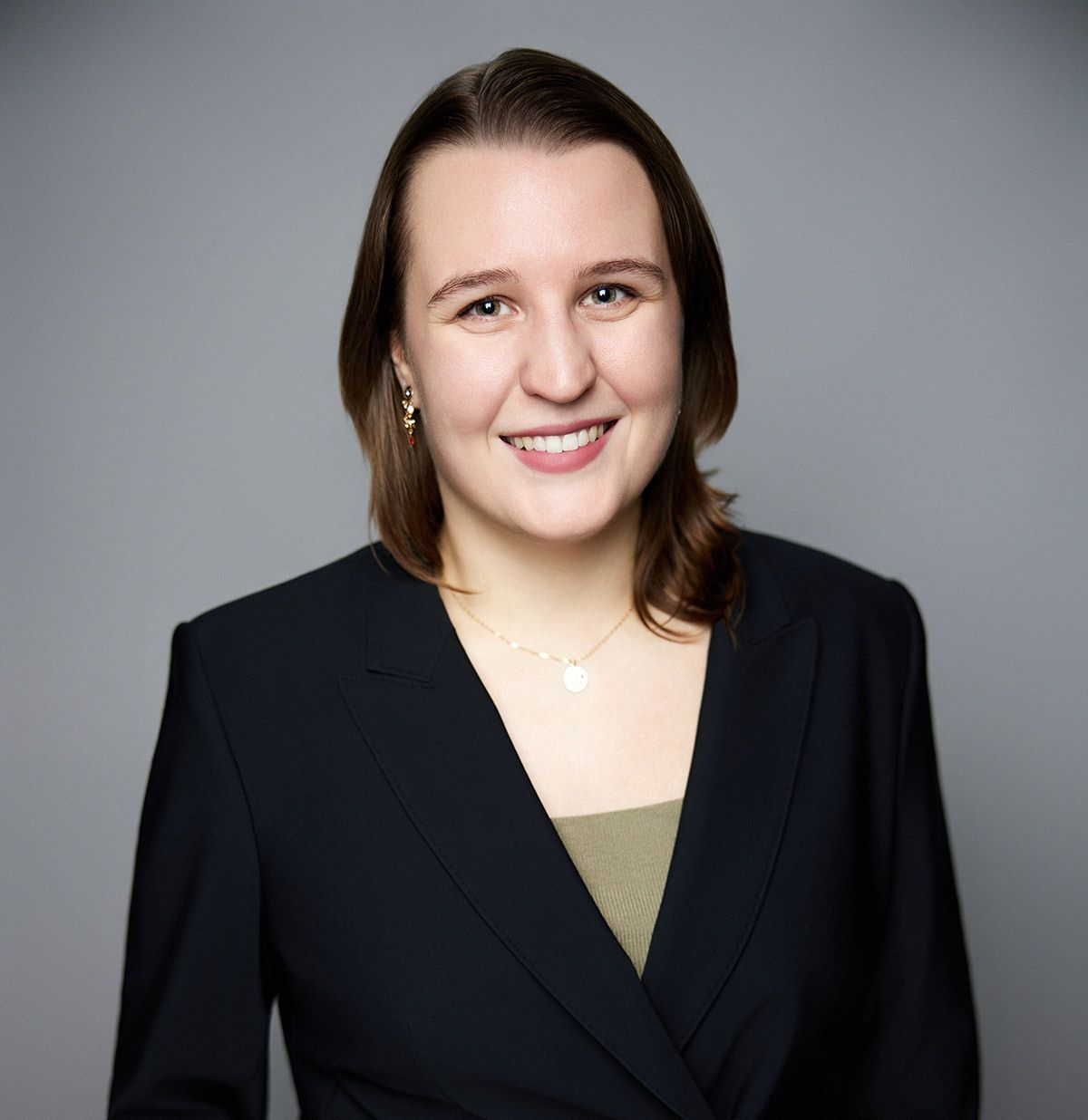 A woman with long brown hair is wearing a white shirt and black pants.