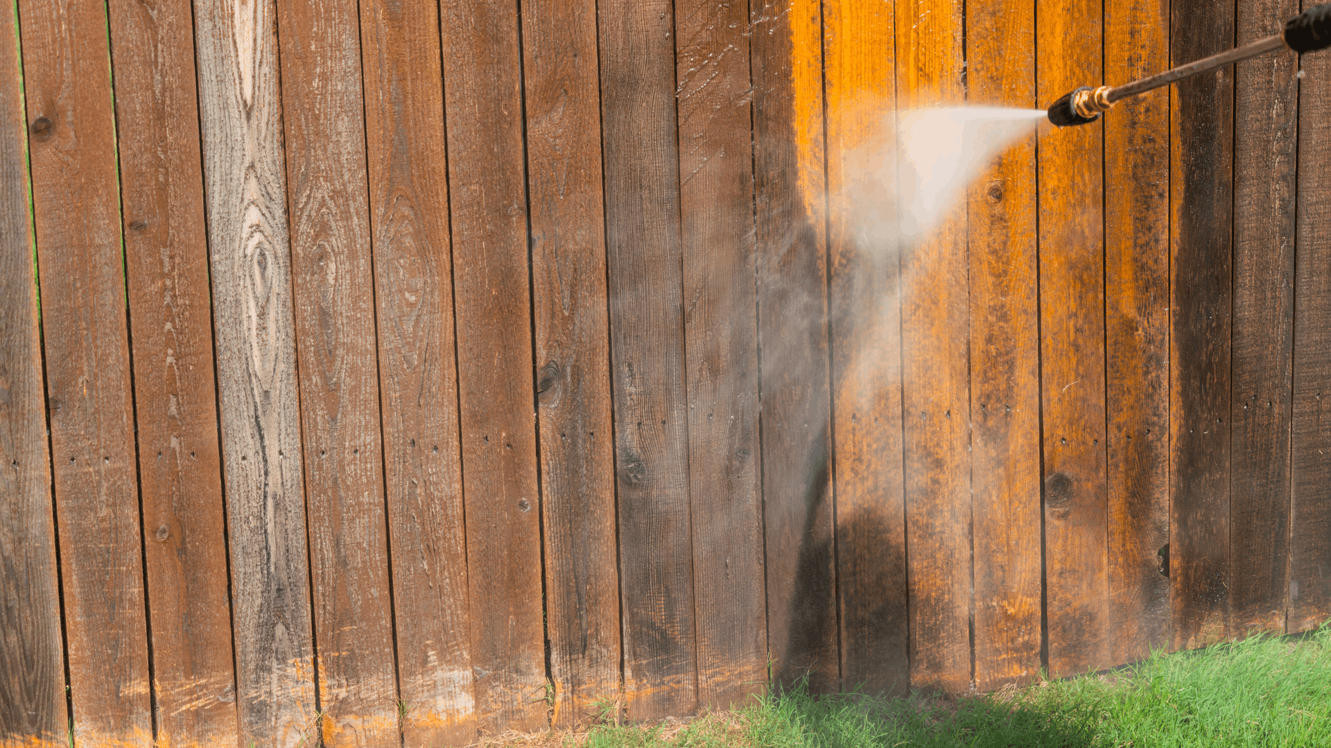 Pressure washing a weathered, brown wooden fence, revealing fresh orange wood — Rohan's Maintenance in Robina, QLD