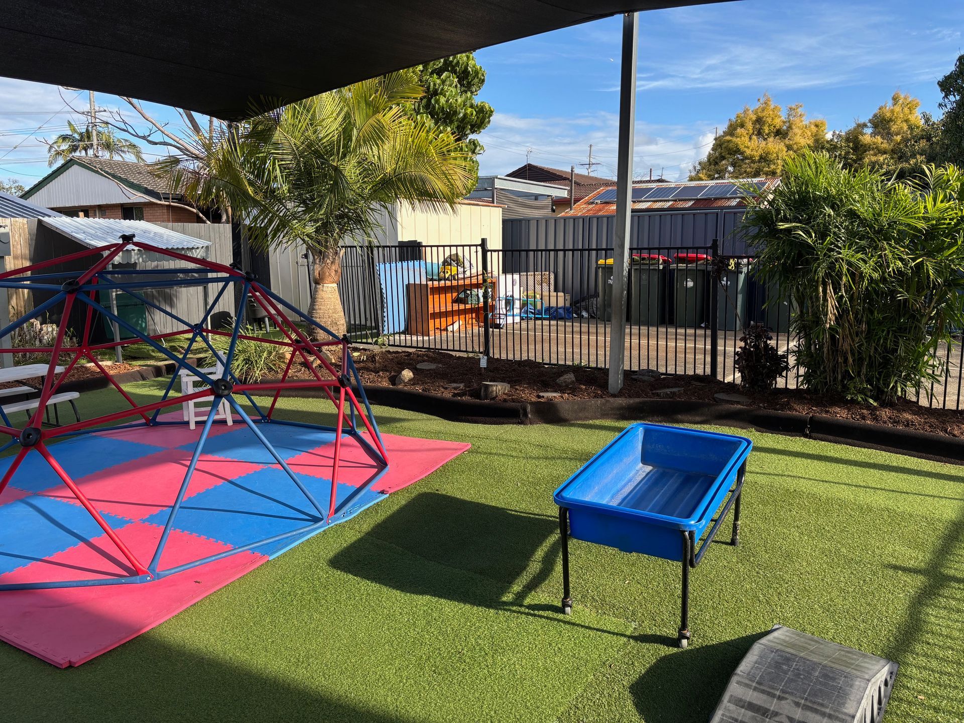 Outdoor play area with artificial turf, sand pit, and wooden play structures — Rohan's Maintenance in Robina, QLD