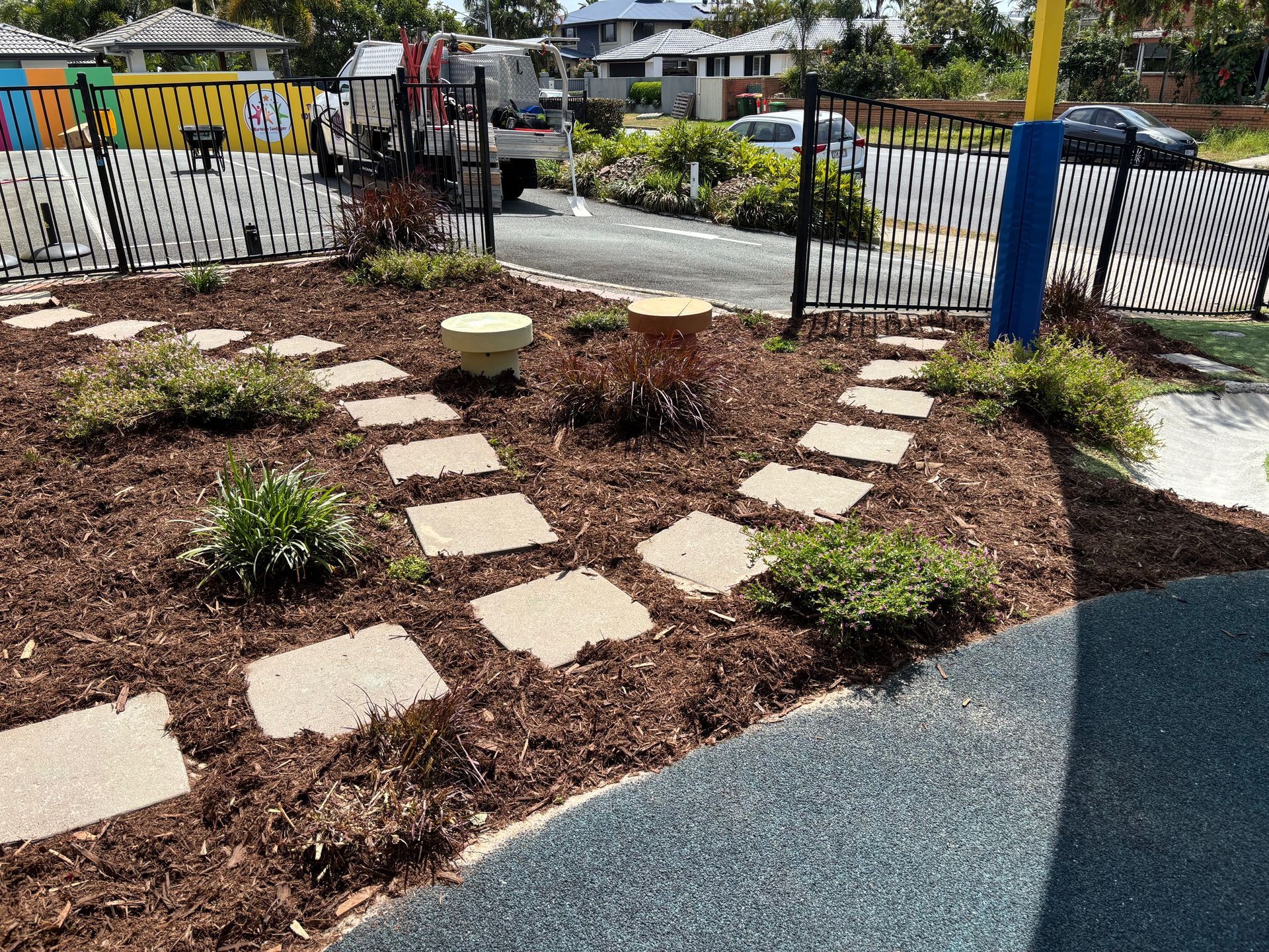 Garden path with wood chip and gravel walkways, shrubs, and a large rock  — Rohan's Maintenance in Robina, QLD