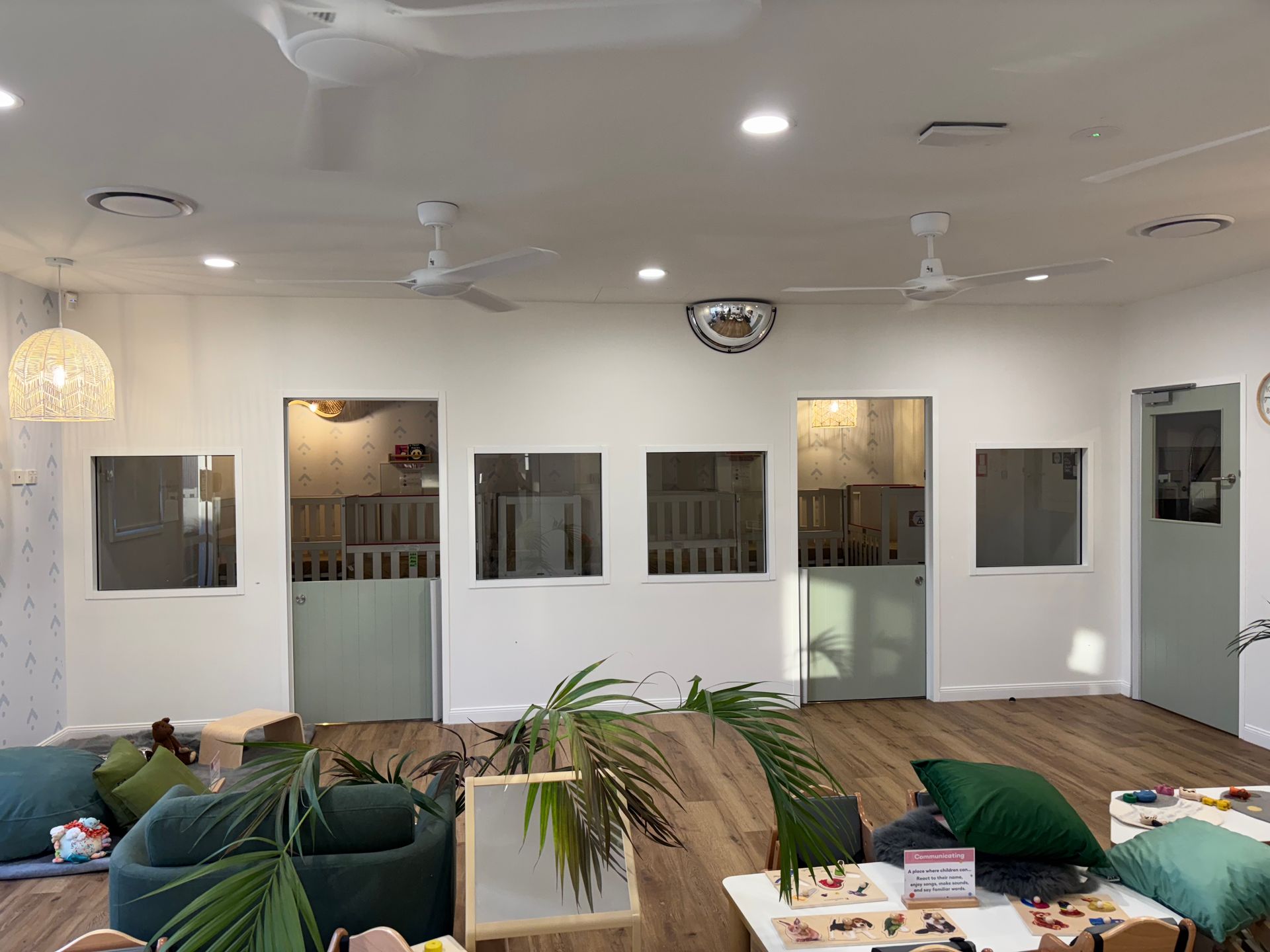 Bright room with crib-lined rooms, ceiling fans, and a disco ball. Green and white accents with wooden floors — Rohan's Maintenance in Robina, QLD