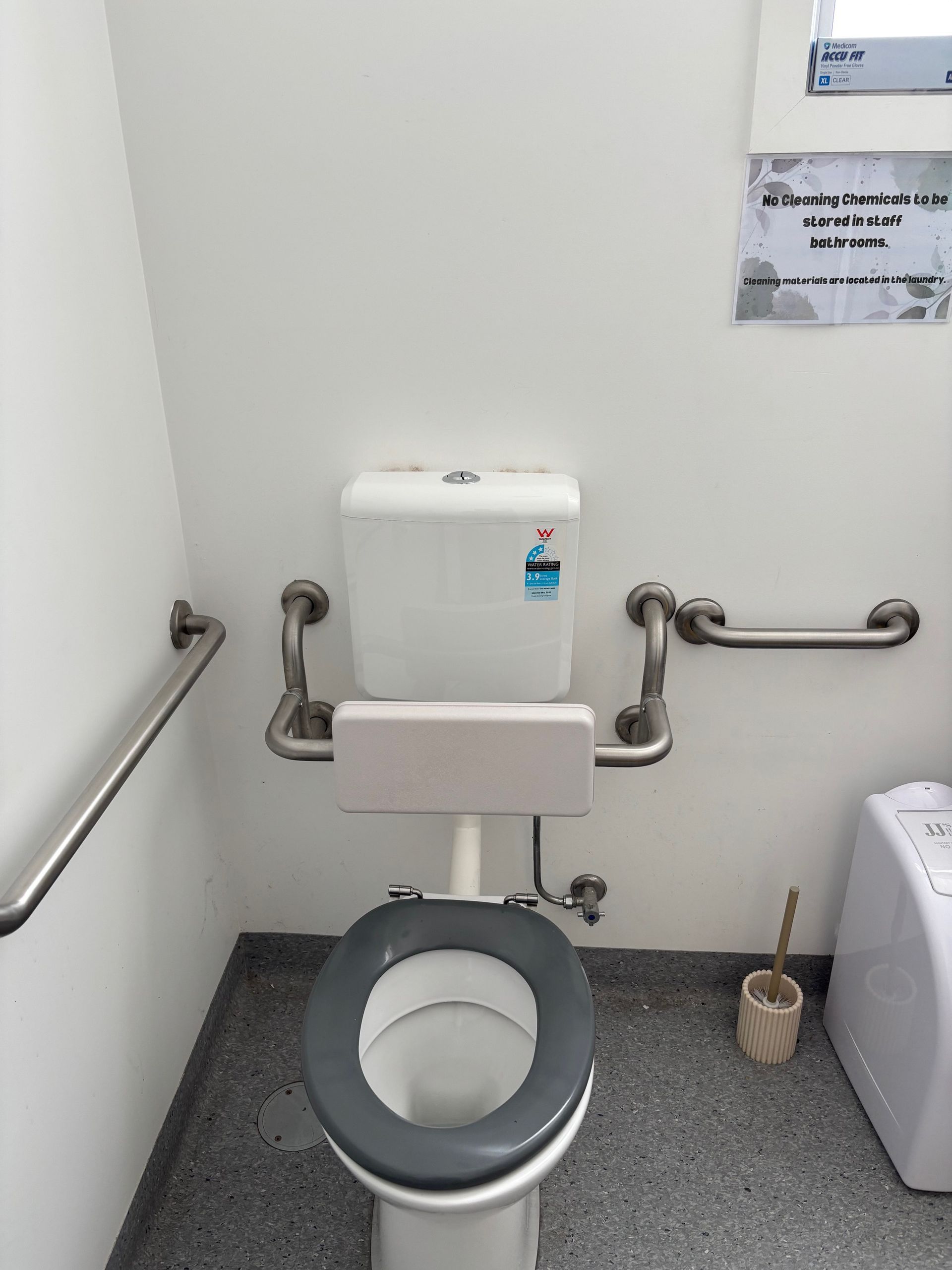 Accessible bathroom with toilet, grab bars, and a toilet brush — Rohan's Maintenance in Robina, QLD