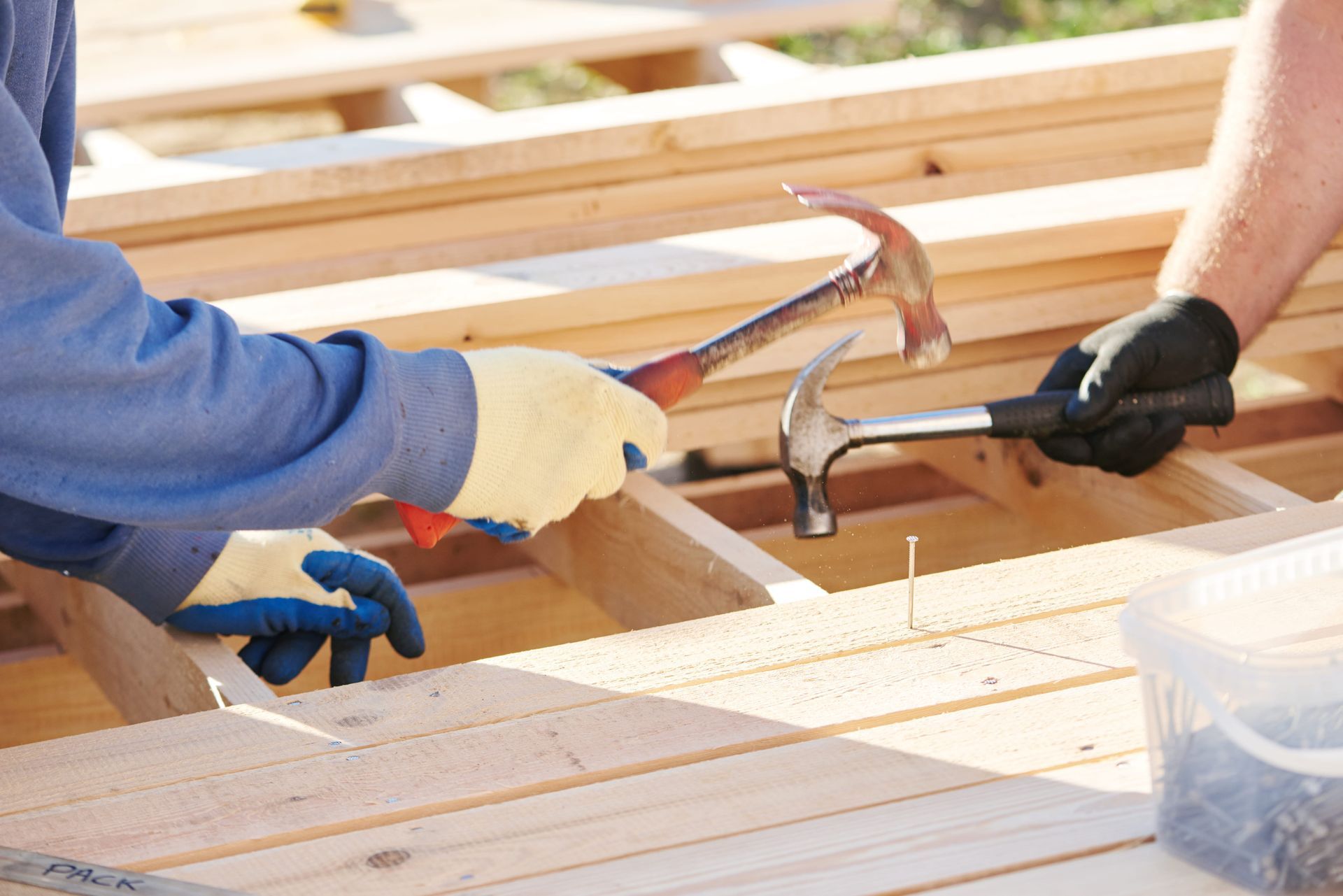 Two people hammering wood planks, construction site, close-up — Rohan's Maintenance in Robina, QLD