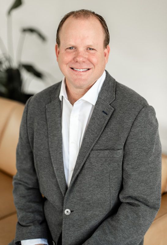 A man in a suit shakes hands with another man in a blue shirt