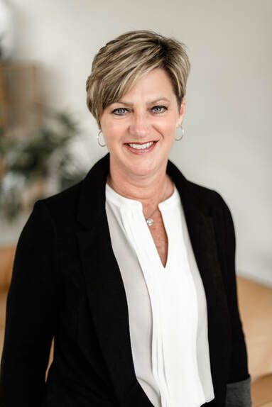 A man in a suit shakes hands with another man in a blue shirt