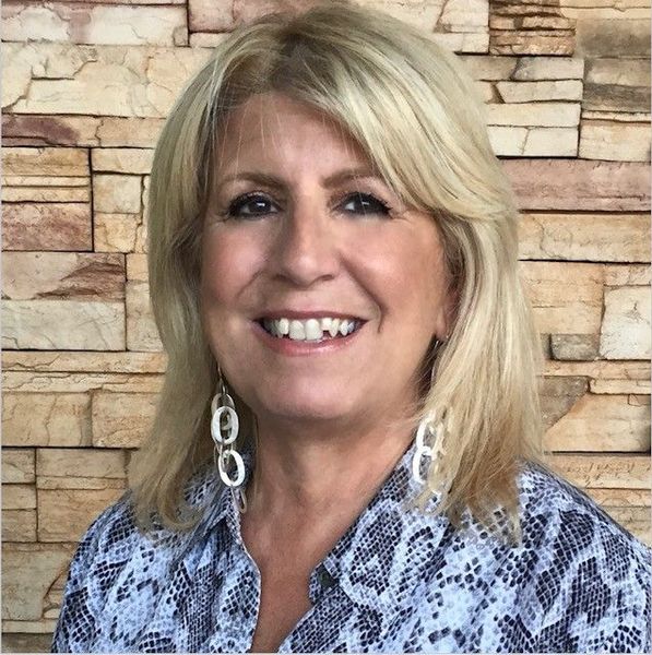 A man is holding a dog in his arms and the dog is wearing a sweater.