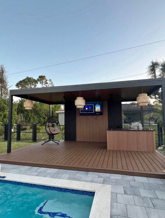 Bright kitchen with white cabinets, island with brown barstools, and black-framed windows.