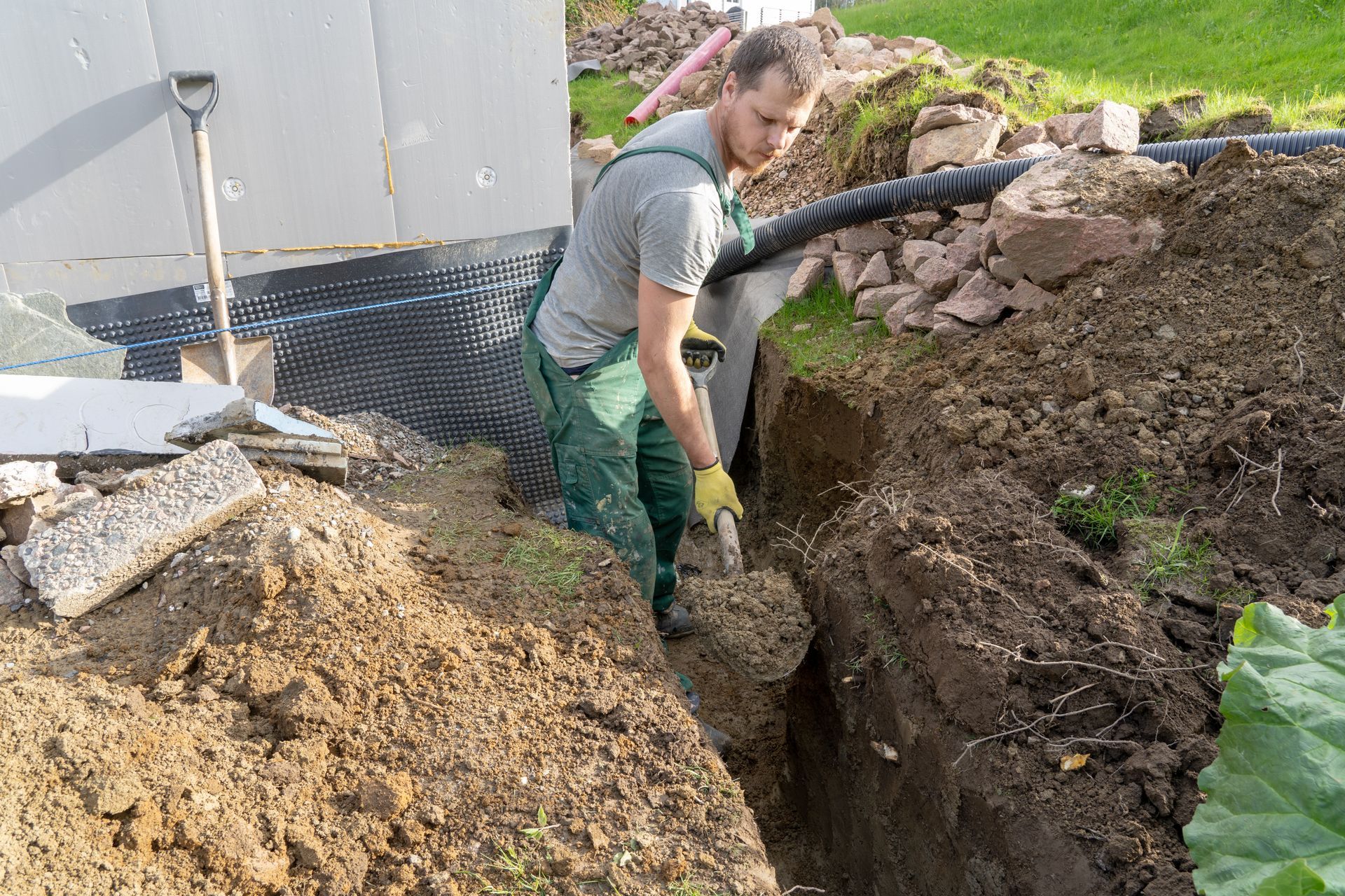 Worker digging a trench to repair a drainage pipe.