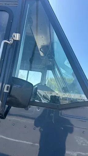 View of a vehicle cabin; open window. Blue sky visible. Shadow of a person below.