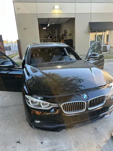 Black BMW with open doors, parked outside a building.