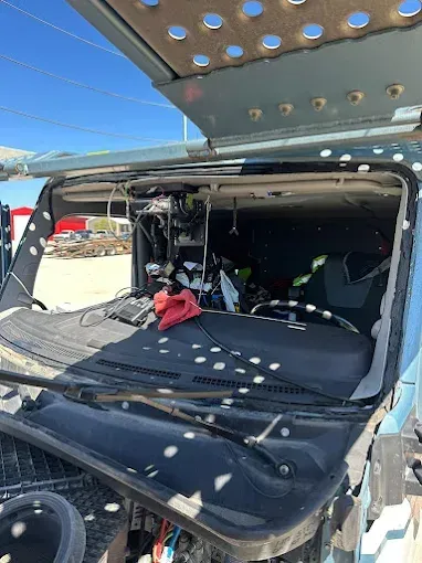 Interior view of a blue truck cab. Dashboard, windshield, and various items inside visible.