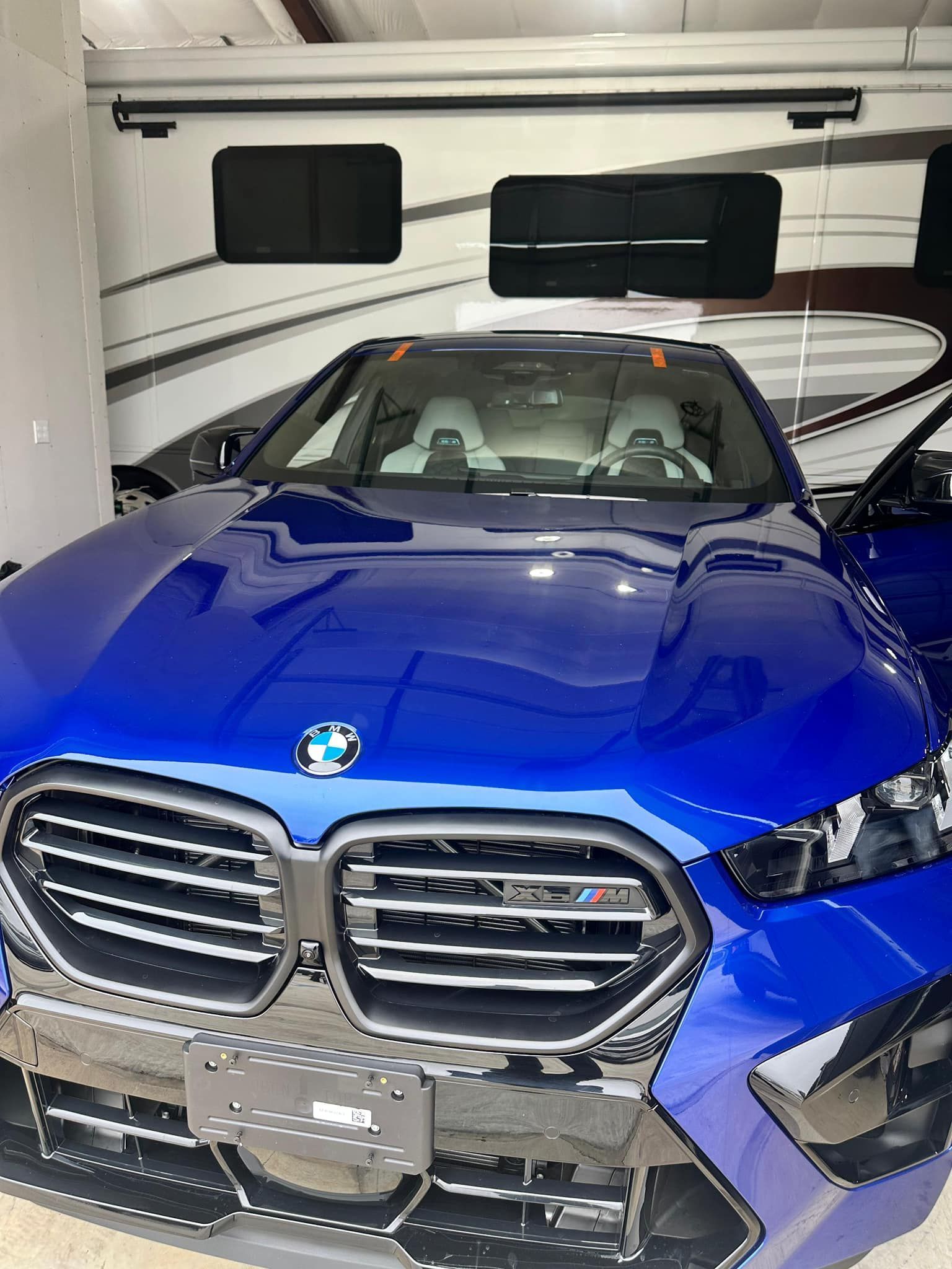 Blue BMW SUV parked inside a garage with an RV in the background.